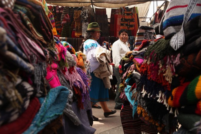A pair of locals walks through the large market of Otavalo. A lot of local women wear hats similar to this one. Photo: Alex Washburn